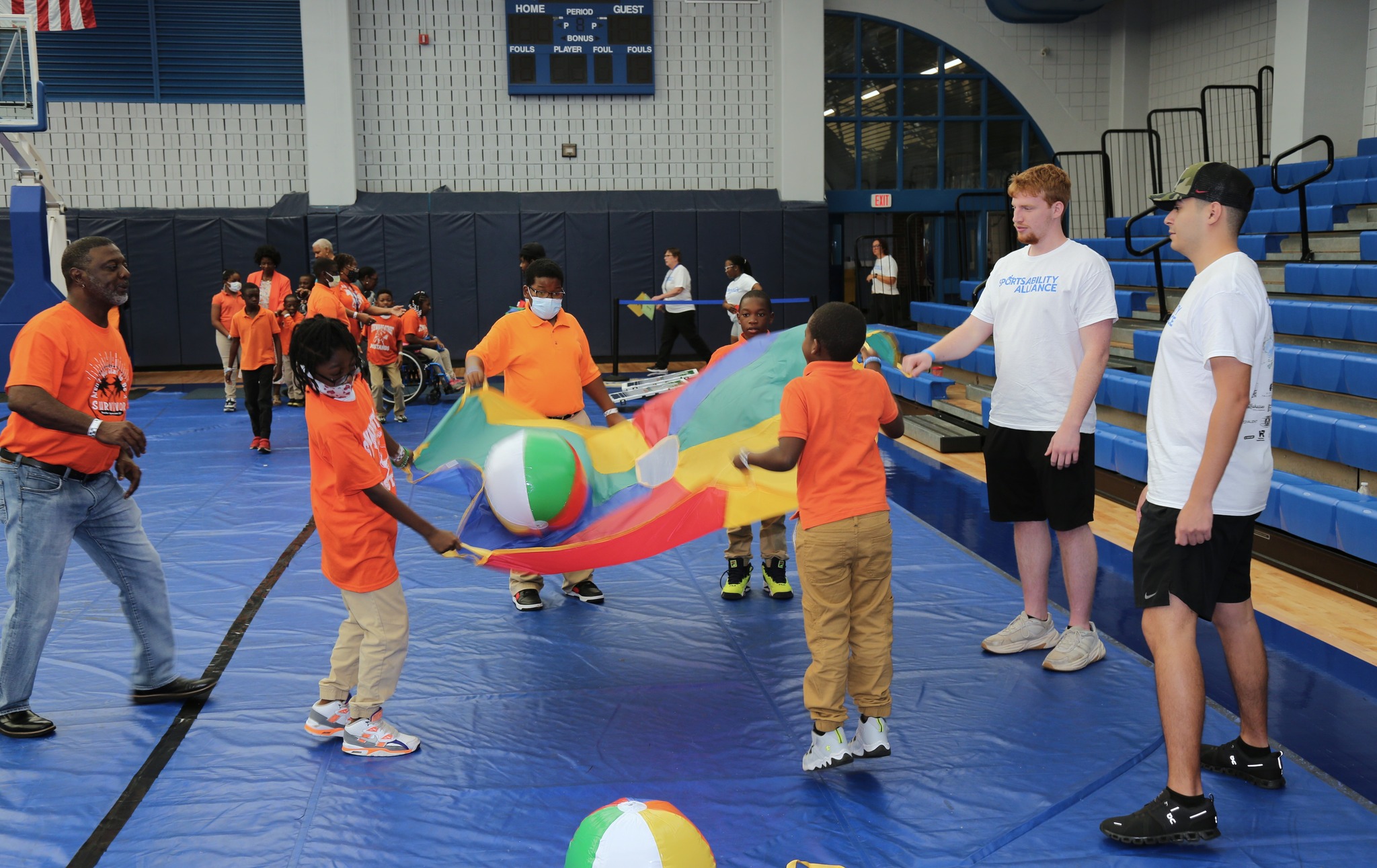 people holding a parachute and playing with a beach ball in a gym