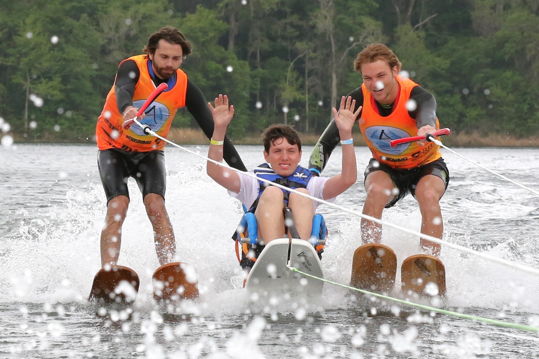 person with a disability doing sit skiing with two assistants 