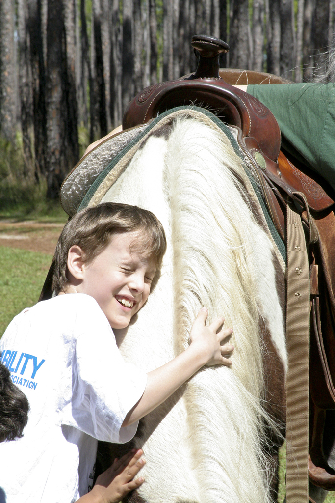 photo of a boy hugging a horse